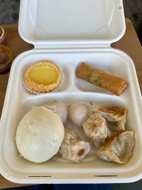 Picture of a takeout box with assorted dumplings and dim sum items