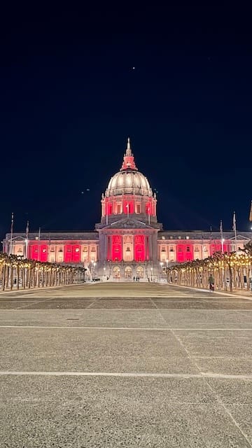 Picture of San Francisco City Hall lit up in red and gold