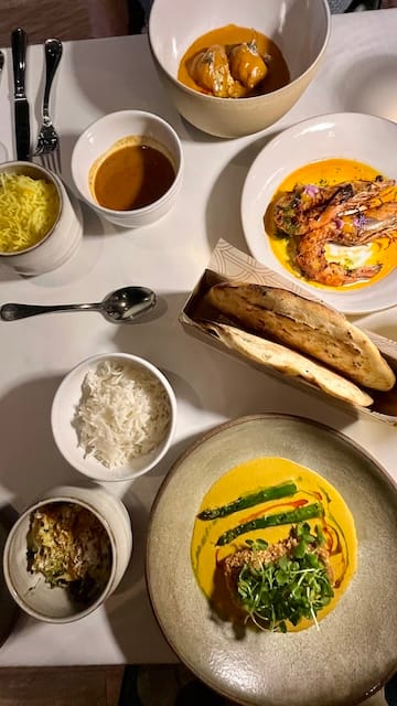 Picture of a table of various Indian dishes and silverware