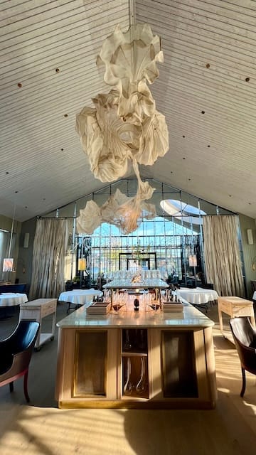 Photo of a dining room with tall ceilings, a large chandelier, and bar in the middle