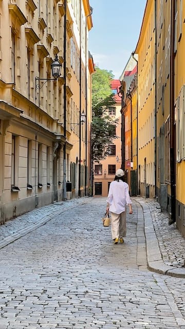 Photo of a women shot from behind walking between colorful buildings