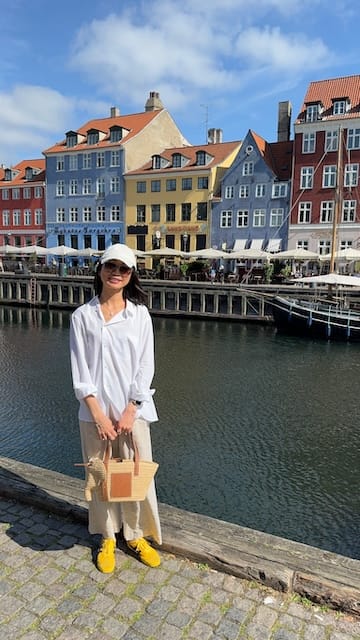 Photo of a woman standing on a canal in front of colorful buildings