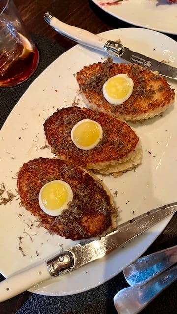 picture of 3 grilled cheese sandwiches with a quail egg and truffles on a white plate