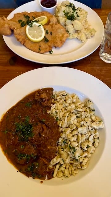 picture of a plate of fried pork and potatoes on top of a plate of beef stew