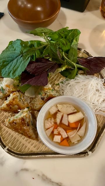 Picture of a plate of patties, noodles, greens, and dipping sauce