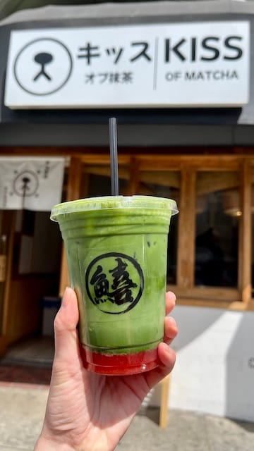 Picture of a cup of matcha with a straw in front of a store
