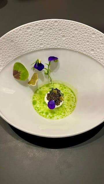 Picture of a white bowl with caviar on top of yogurt with flowers on the side