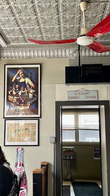 Picture of a wall in a restaurant with photos and a sign at a doorway that says "elegant dining room"