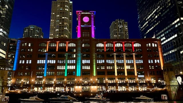 Picture of a building on the river at night with rainbow lights