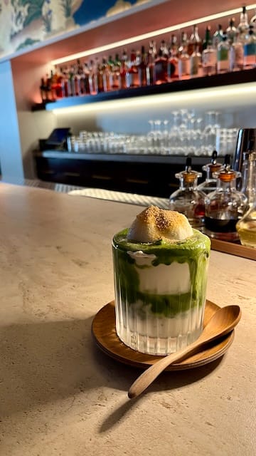 Picture of a matcha and cream drink in a glass on a bar table