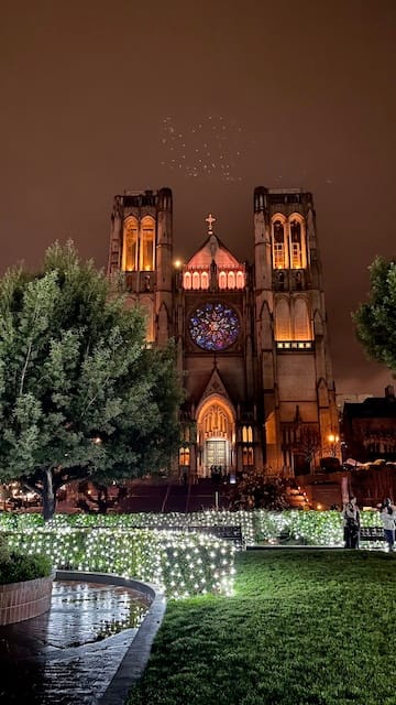 Picture of a park with lights and a bright cathedral in the background