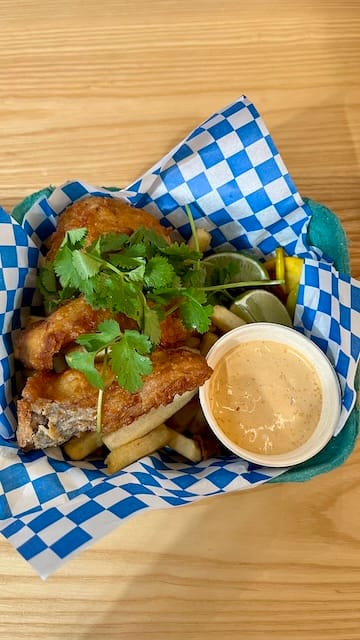 Picture of a fish and chips, pickled vegetables, and sauce