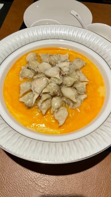 A picture of a crab meat on top of an egg custard in a white bowl