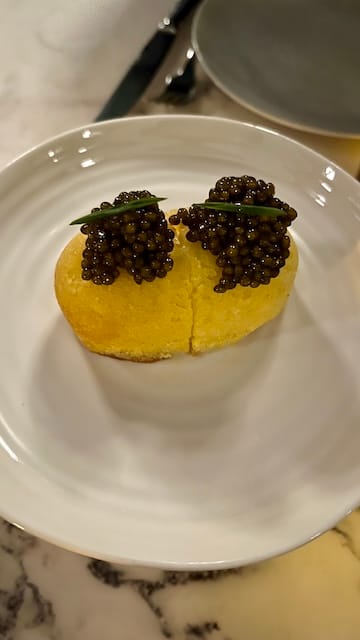 picture of a yellow pastry with black caviar on top